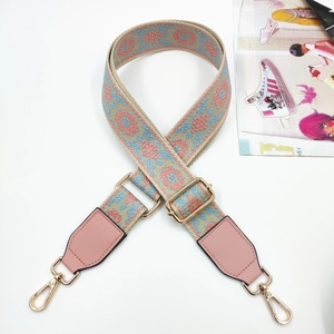 Detail of colorful jacquard bag strap with pink leather ends and golden metal hardware