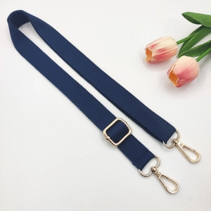Detail of navy blue adjustable canvas strap with light gold metal swivel hooks and buckle