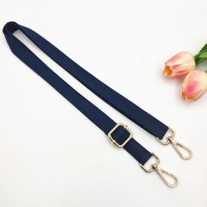 Detail of navy nylon bag strap with polished gold hardware buckles and adjustable slider