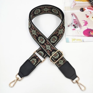 Detail of bohemian floral embroidery strap with golden metal hooks and leather ends
