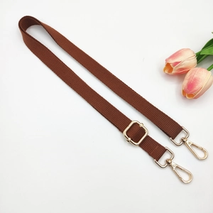 Detail of adjustable brown woven shoulder strap with polished gold metal lobster clasps