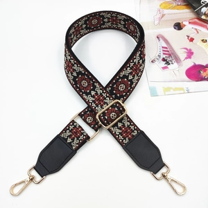 Close-up of geometric floral jacquard bag strap with gold metal hardware and leather ends
