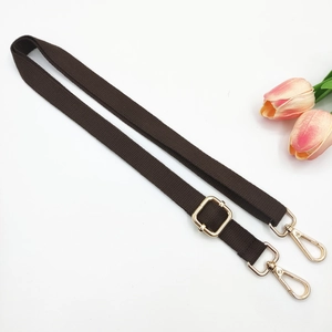 Detail of adjustable dark brown bag strap with gold metal lobster clasps and slider