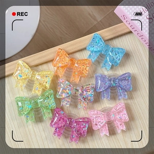 Collection of colorful bow-shaped phone grips with glitter resin detail on wood