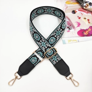 Detailed view of ethnic embroidery pattern on wide bag strap with gold metal hardware