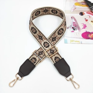 Close-up of ethnic floral woven bag strap with brown leather and gold swivel hooks