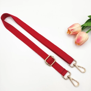 Detail of red cotton bag strap with golden adjustable metal buckle and lobster hooks