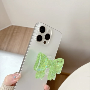 Close-up of a green glitter bow phone socket grip on a white smartphone back