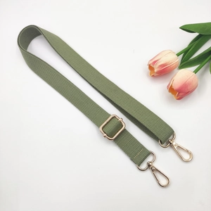 Detail of army green woven shoulder strap with gold metal buckles and adjustable slider