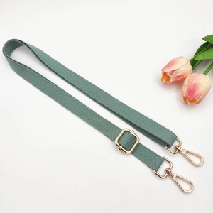 Detail of adjustable cotton crossbody strap in sage green with gold metal buckles