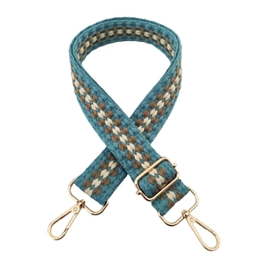 Close-up of woven bag strap with blue wavy pattern and gold metal lobster clasps
