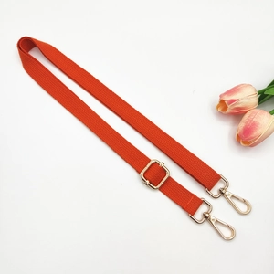 Detail of orange adjustable canvas bag strap with golden metal hooks and fine twill weave