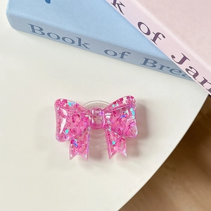 Close-up of pink bow phone grip with heart sequins and glitter in a liquid sand design