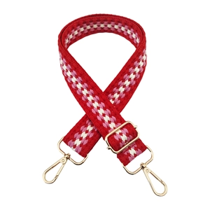 Detail of adjustable woven bag strap with red, white and pink patterns and gold hooks