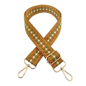 Detail of adjustable woven bag strap with retro geometric pattern and gold metal hooks