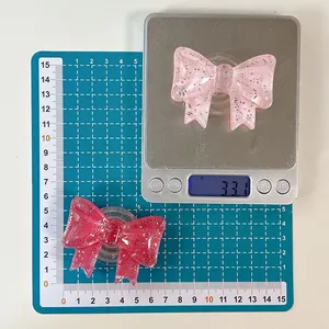 Glitter resin bow phone grip showing 5.5cm size measurement on a cutting mat
