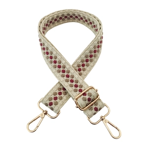Close-up of a wide woven bag strap with geometric dots and gold metal hardware