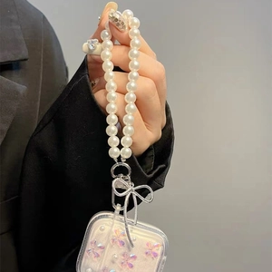 Detail of AirPods case featuring large pearl chain and silver bow pendant charm