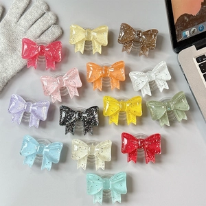 Detailed flat lay of thirteen glitter bow resin phone grips in multiple vibrant colors