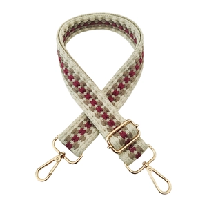 Detail of adjustable woven bag strap in red and beige with gold metal lobster clasps