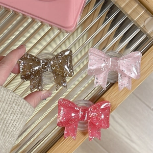 Sparkly glitter bow-shaped phone grip stand in coffee, pink and deep red resin finish