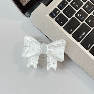 Macro detail of white glitter bow phone grip featuring sparkly resin and a pop socket base
