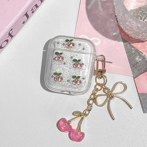 Detail of glittery cherry AirPods case with a metallic bow and resin fruit keychain