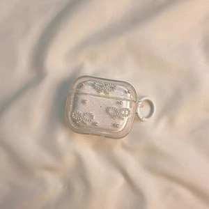 Detalle de funda glitter para AirPods Pro con lazos de perlas y gancho redondo