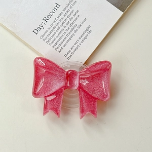 Dettaglio dell'impugnatura per telefono a fiocco glitter rosa su tavolo crema