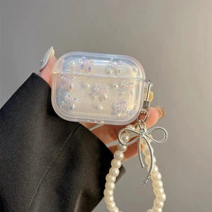 Detail of clear AirPods case with pearl chain and holographic bow charm decoration