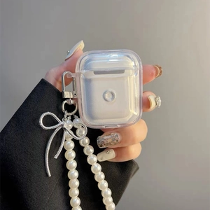 Clear AirPods case with pearl chain strap and silver bow charm held by a model