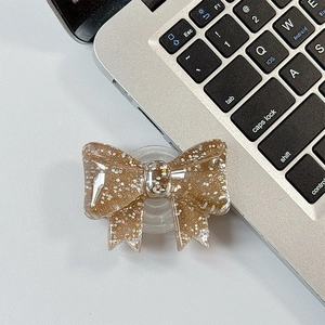 Detail of a brown glitter bow phone grip made of translucent resin on a laptop