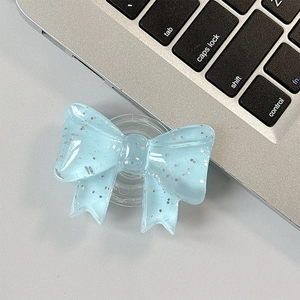 Detail of light blue glitter bow phone grip tok on laptop keyboard with sparkling finish