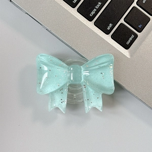 Detail of mint green bow phone grip with silver glitter on a laptop keyboard