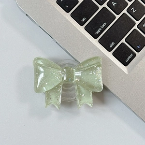 Close-up of light green glittery bow phone grip stand on laptop keyboard