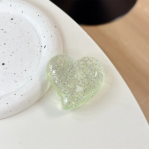 Macro view of a light green glitter heart phone grip with sparkling resin texture