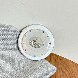 Detail der magnetischen Handyhalterung mit schillerndem Blumendesign und silberner Blütenverzierung