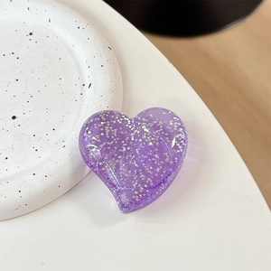 Close-up of heart-shaped phone grip featuring purple glitter resin and glossy finish