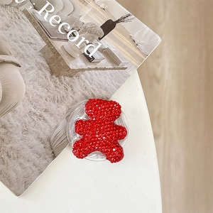 Macro detail of bear phone grip featuring vibrant red rhinestones on a white background