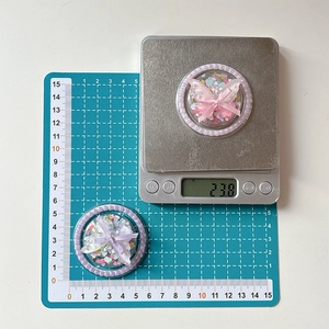 Detailed view of 5.5cm bow phone grip showing 23.8g weight on a digital scale
