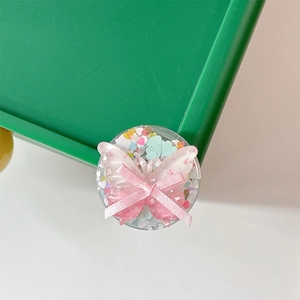 Close-up of pink bow phone grip with colorful heart sequins in a clear round base