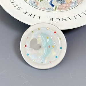 Detail view of rhinestone-embellished phone grip with blue dolphin and silver heart