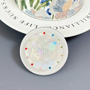 Close-up of a pearl white magnetic phone grip with embossed butterfly and colorful rhinestones