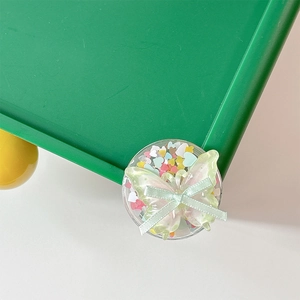 Close-up of cute bowknot phone grip with heart sequins and green butterfly charm
