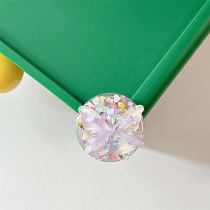 Close-up of heart sequins and purple bow on a clear acrylic phone socket grip
