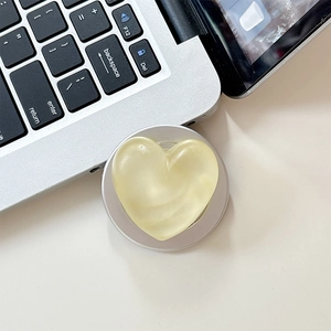 Close-up of cream heart phone grip with silver magnetic base on a laptop keyboard