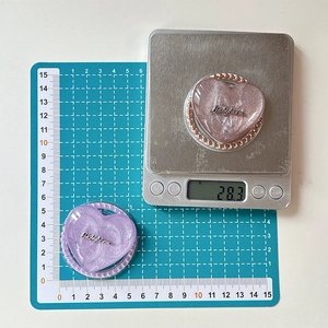 Detail view of heart-shaped Magsafe grips with glitter and pearls, showing 5.5cm size and 28g weight