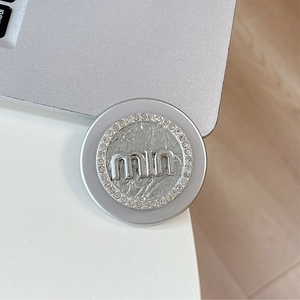 Macro detail of silver magnetic phone grip with miu logo and sparkling rhinestones