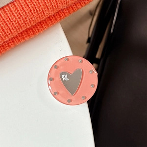 Close-up of a pink resin phone grip with silver heart and rhinestones on orange knit fabric
