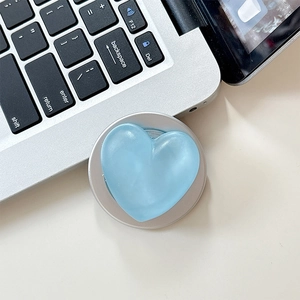 Detail of light blue heart-shaped phone grip stand on a silver laptop surface